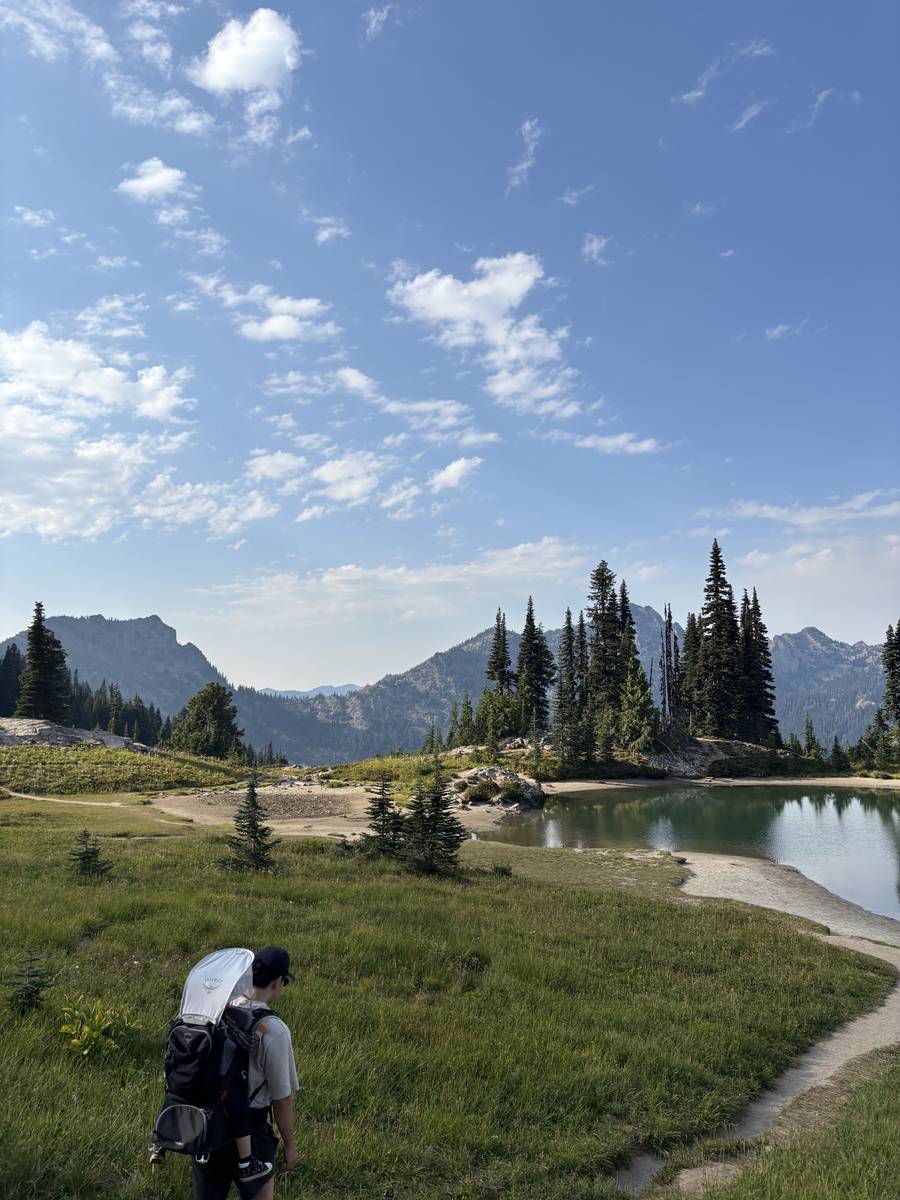 A family hike past an alpine lake and meadow in the mountains